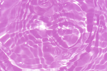 Purple water with ripples on the surface. Defocus blurred transparent pink colored clear calm water surface texture with splashes and bubbles. Water waves with shining pattern texture background.