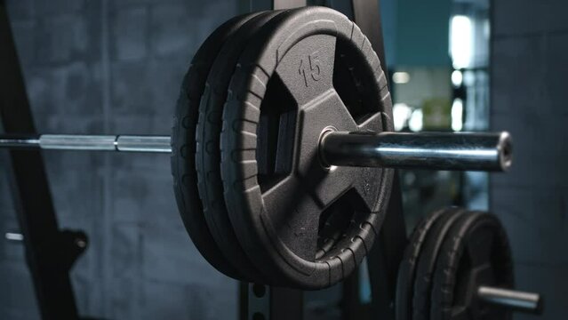  close up of handsome bodybuilder guy prepare to do exercises with barbell in a gym, keep barbell plate in hands. High quality 4k footage