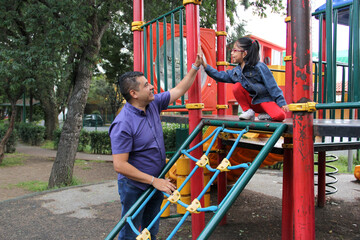 Divorced single dad and 4-year-old daughter Latino brunettes play on outdoor park playground spend quality time together tech-free