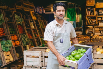 middle-aged Latino man, greengrocer in his organic shop with green apples in his hands