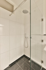 a modern bathroom with black and white tiles on the floor, glass shower stall door and toilet in the corner