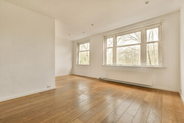 an empty room with wood flooring and large windows looking out to the trees outside in the room is white