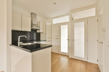 an empty kitchen with wood flooring and white cupboards on either side, there is a sink in the corner
