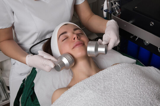 Led Light Therapy.Chromotherapy procedure with Hydrafacial device.Woman doing LED face therapy in blue