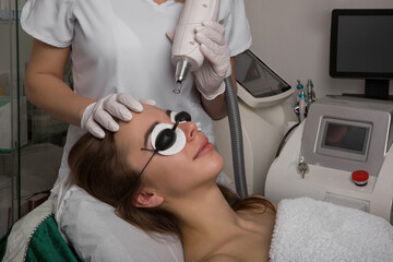 beautician holding beauty laser near woman face,protective eyewear, spa procedures with laser and...