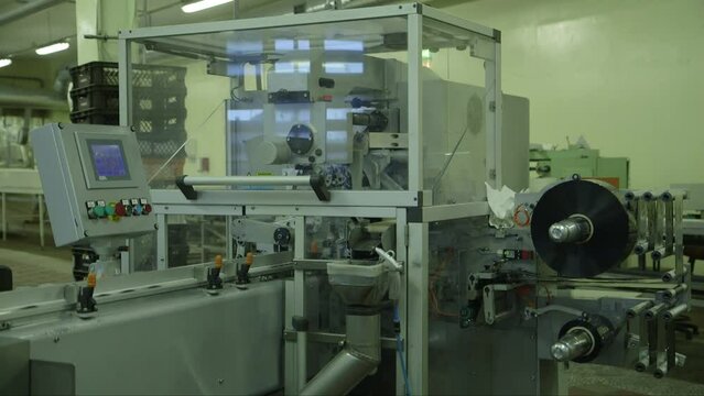 static wide shot of chocolate packaging machine in action in a chocolate factory
