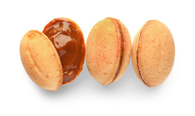 Delicious nut shaped cookies with boiled condensed milk on white background, top view