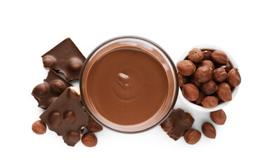 Chocolate pieces, glass of delicious paste and hazelnuts on white background, top view