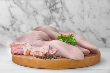 Raw beef tongues, peppercorns and parsley on white wooden table, closeup