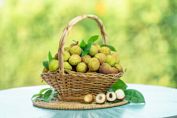 Green Lychee fruit in wooden basket over blur greenery background, Green Lychee or Chinese Cherry fruit over green natural Blur background.
