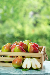 Red pear in wooden box over blur greenery background, Red pear in basket on green bokeh background.