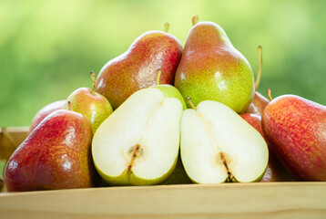 Red pear in wooden box over blur greenery background, Red pear in basket on green bokeh background.