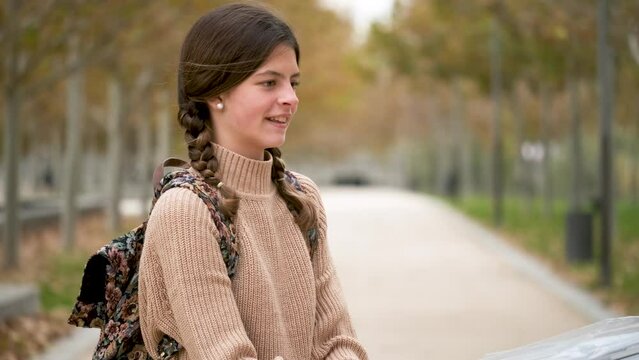 Preteen girl opening an umbrella, smiling and looking at camera outdoors in autumn. Back to school.