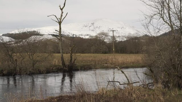 Scottish mountain with snow behind a flowing creek in spring