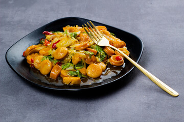 Saute sweet spicy sausage with black plate. Dark mood photography.