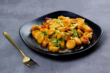 Saute sweet spicy sausage with black plate. Dark mood photography.