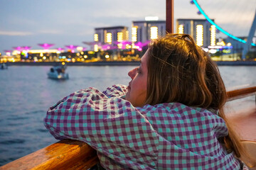 Fototapeta na wymiar Young beautiful woman travels on an Arabic boat in Dubai Marina in Dubai, UAE