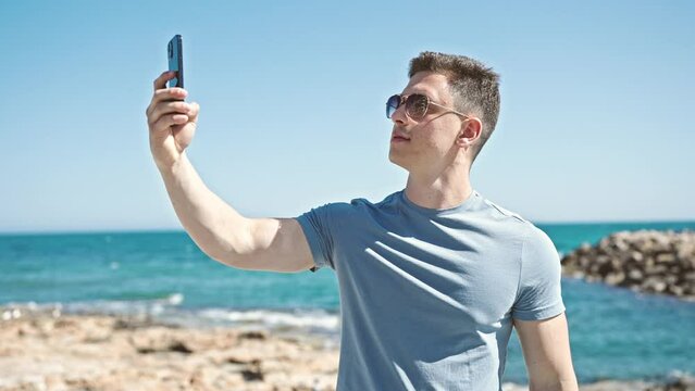 Young hispanic man tourist making selfie by the smartphone at seaside