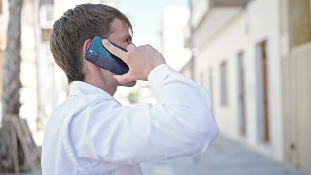 Young caucasian man talking on smartphone at street