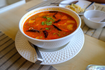 Tom Yam Kung ,Prawn and lemon soup with mushrooms, thai food in white bowl top view real dish in Dining setting