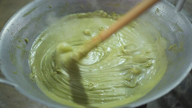 cooking liquid rhombic pandan leaf stirring or closeup freshly kanom piak poon bai toey and green coconut sweet pudding with smoke steam heat on hot pan charcoal stove by thailand nature dessert food