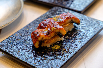 Unagi or Eel Nigiri Sushi Served on a Black Luxury Textured Plate, Japanese Seafood Delicacy, Fine Dining Presentation