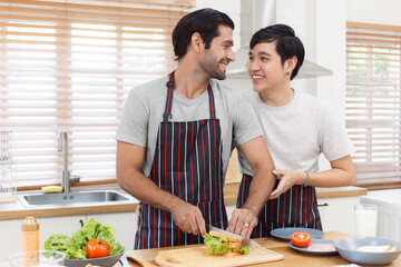 Happy cheerful LGBTQ+ gay romantic couple preparing and making a sandwich together in the kitchen. Diversity in ethnicity, nationality, and sex concept. LGBTQ+ married people lifestyles.