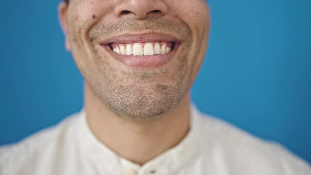 Young hispanic man close up of smile over isolated blue background