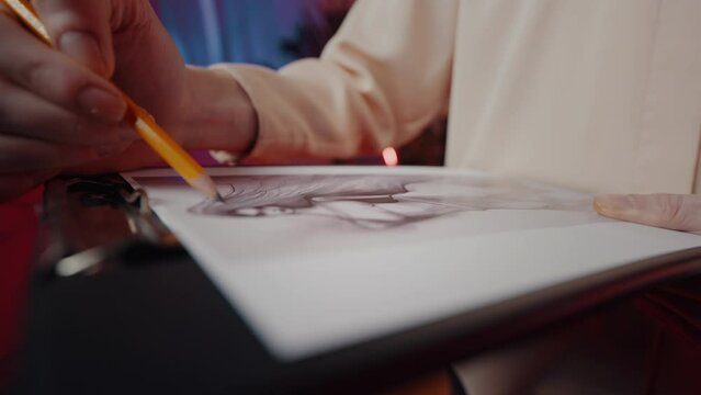 Slow motion fashion designer draws sketches, creating clothing on a paper using pencil technique