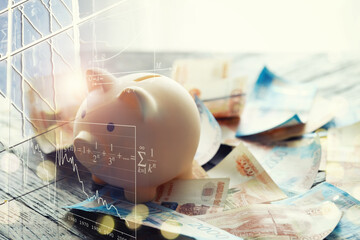 A piggy bank in the form of a pink pig stands on the wooden table with russians money, inscription five, two and one thousand ruble bills.