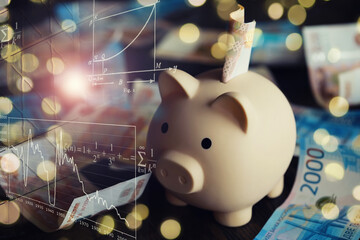 A piggy bank in the form of a pink pig stands on the wooden table with russians money, inscription...