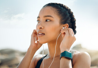 Woman with earphones, fitness at the beach and listening to music for motivation and workout...