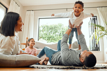 Family, father lifting son and playing in living room with fun and mother with daughter bonding at...
