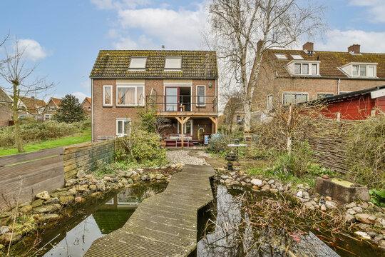 a house in the netherlands, with a small pond and wooden walkway leading up to its front door - stock photo