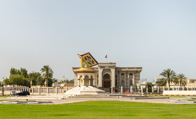 Obraz premium The Monument in the form of an open holy book Koran and the Sharjah Governmental Building on the Cultural Square in Sharjah city, United Arab Emirates