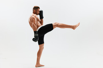Fototapeta premium Man athletic bodybuilder poses in boxing gloves with nude torso abs in full-length background, boxing and martial arts. Advertising, sports, active lifestyle, light, competition, challenge concept. 