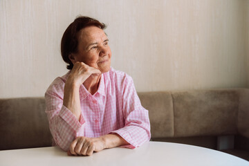 Head shot close up peaceful older woman dreaming thinking about good future alone, sitting on couch at home alone, dreamy mature female looking in distance, feeling satisfied