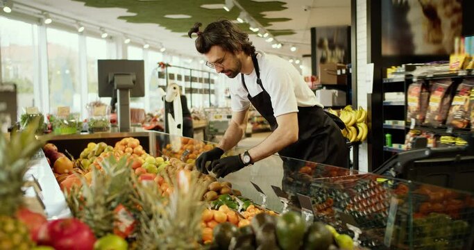 Fruitful Delights: A Supermarket Employee Showcasing Fresh Kiwi