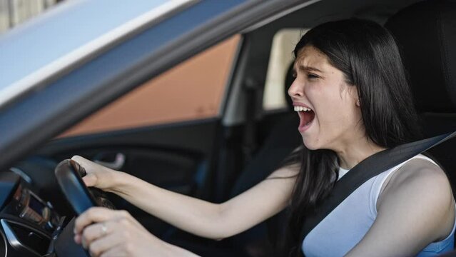 Young beautiful hispanic woman tired sitting on car yawning at street