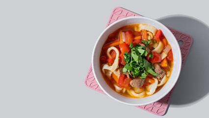 Lagman cooked soup with beef and vegetables on grey background. Copy space	
