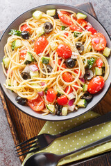 Cold Italian spaghetti salad features fresh veggies and lots of yummy dressing closeup on the bowl on the table. Vertical top view from above