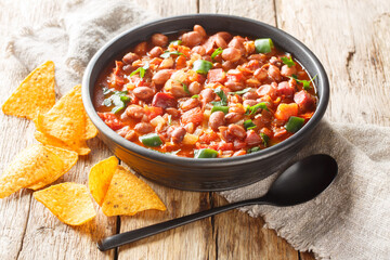 Mexican pinto bean stew with tomatoes, sausages, bacon and onions close-up on a bowl on the table. horizontal