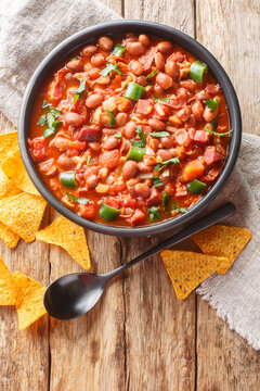 Frijoles charros or charros beans mexican traditional food with chorizo bacon and onions spicy food closeup on the bowl on the table. Vertical top view from above