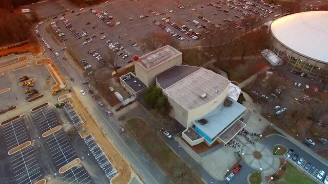 Aerial Tilt Up Shot Of Vehicles In Parking Lots By Bojangles Coliseum, Drone Flying Over City Against Orange Cloudy Sky At Sunset - Charlotte, North Carolina