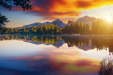 A fabulous evening view of calm lake Strbske pleso, surrounded by mountains. National Park High...