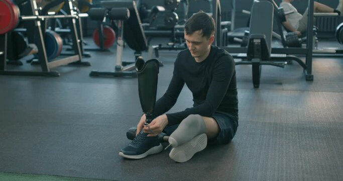 happy motivated ambitious Disabled Caucasian young man athlete tying shoe laces Slow motion, people with disabilities lifestyle concept Never give up