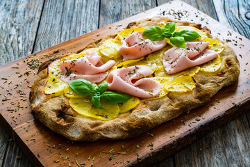 Mortadella and potato pizza on wooden table