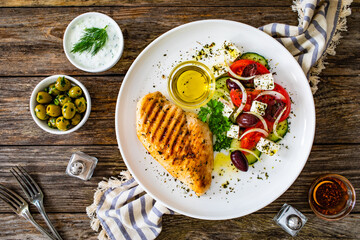 Seared chicken breast and Greek salad on wooden table
