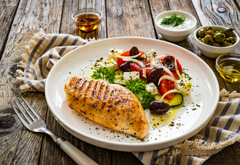 Seared chicken breast and Greek salad on wooden table
