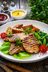 Grilled pork loin steaks with green beans and fried potatoes on wooden table
